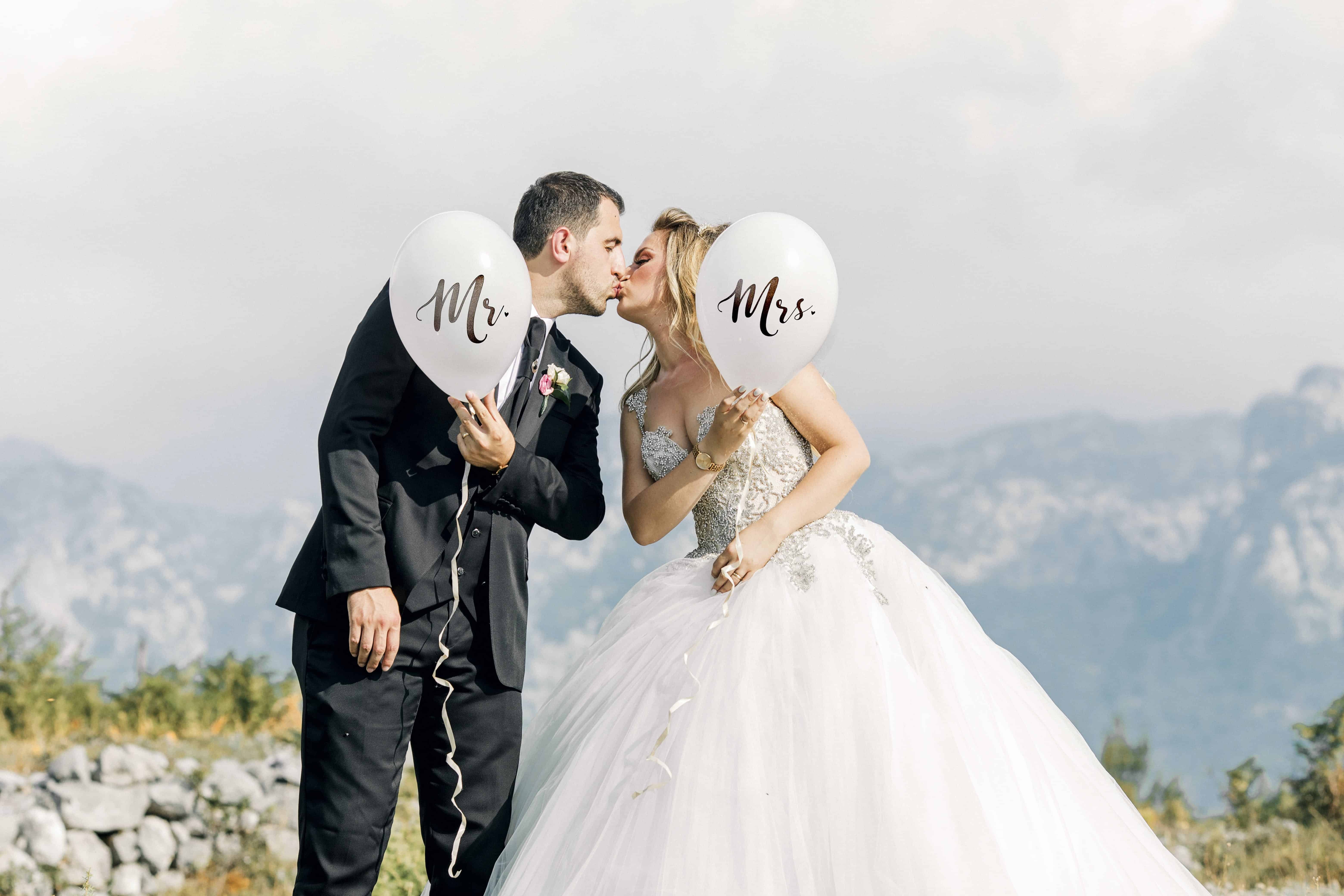 Man and Woman Kissing While Holding Balloons