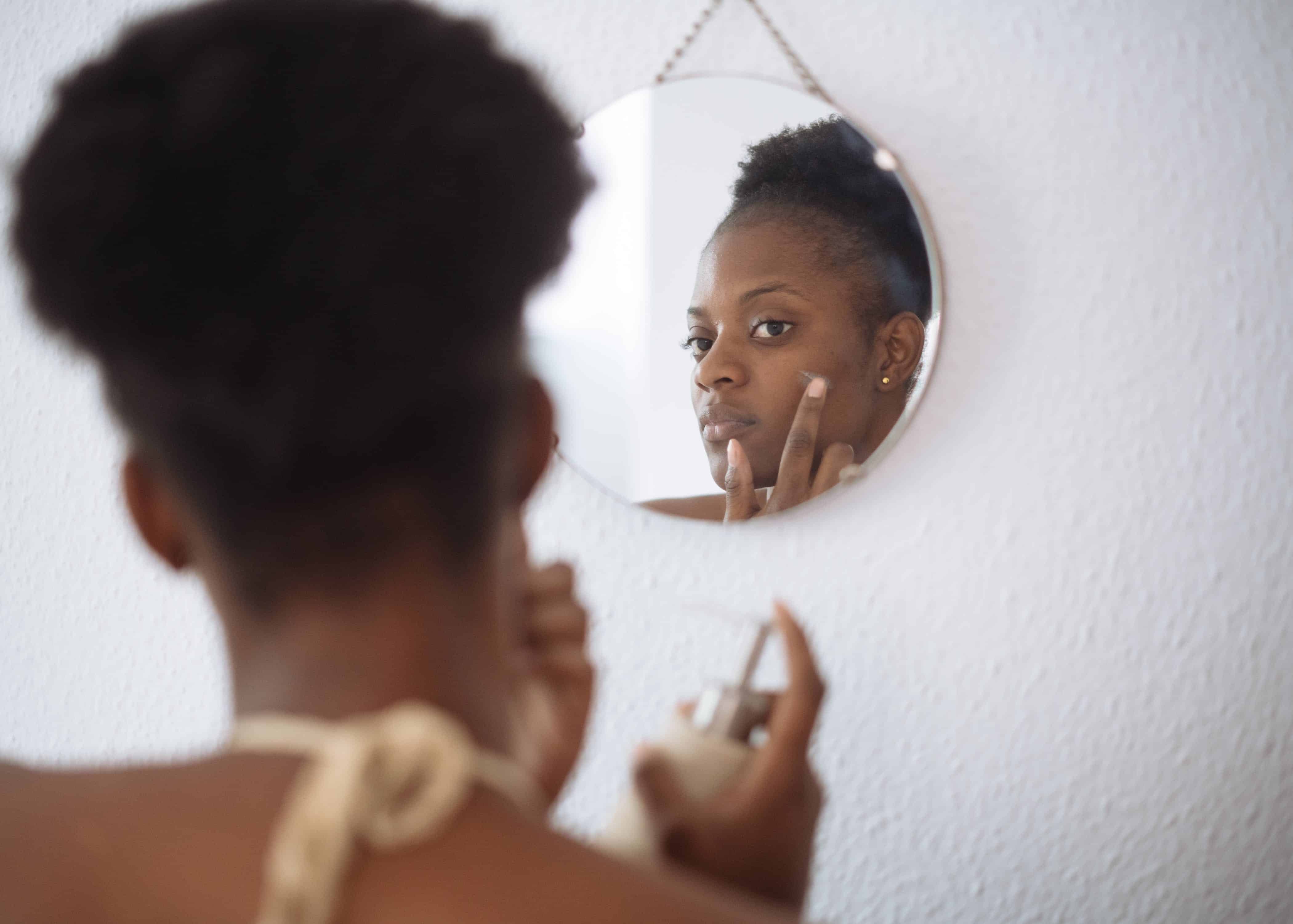 Focused woman applying cream on face in bathroom