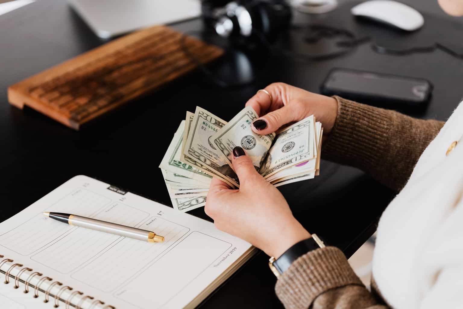 Crop woman counting money at modern office table