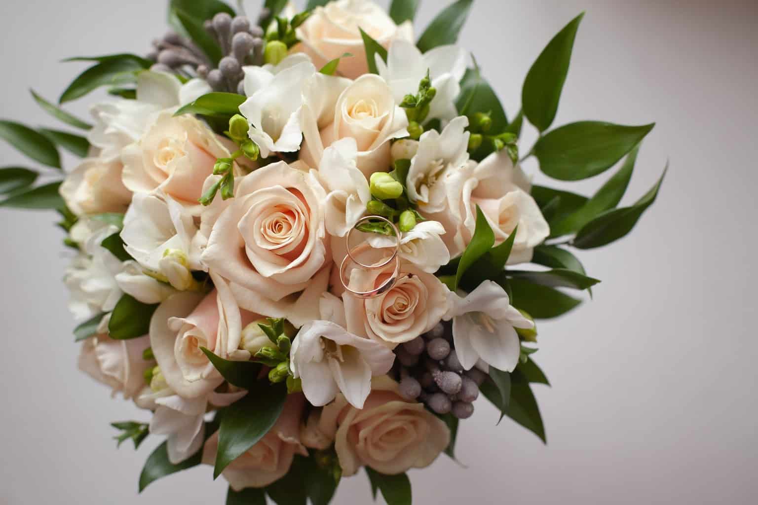 Flower bouquet with roses and green plants on white background