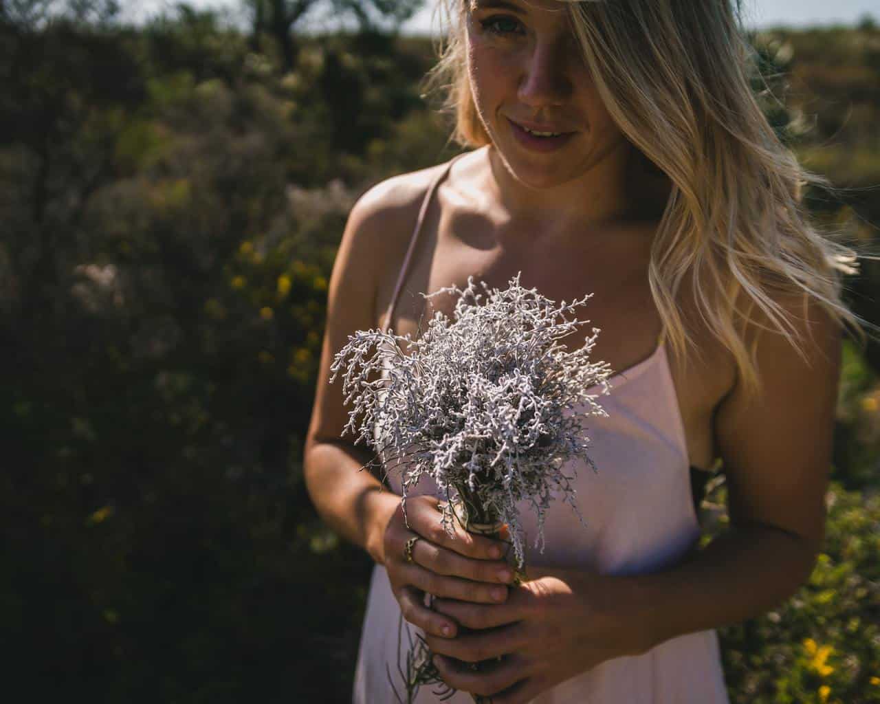 woman in white tank top holding white and pink flowers