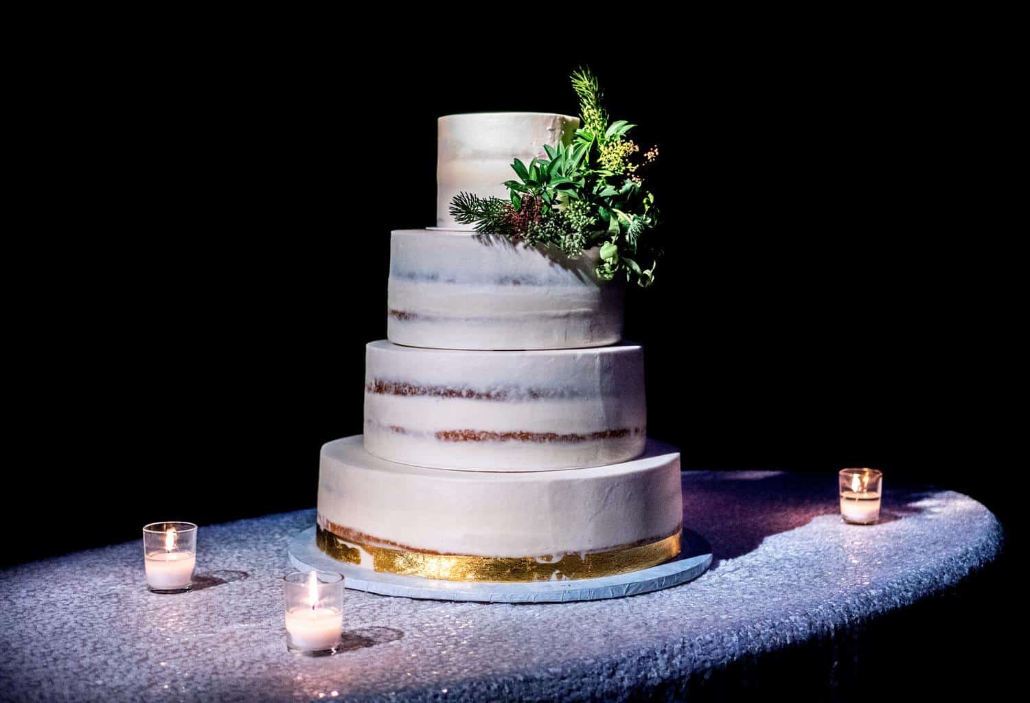 4-tier cake on top of gray table with three votive candles