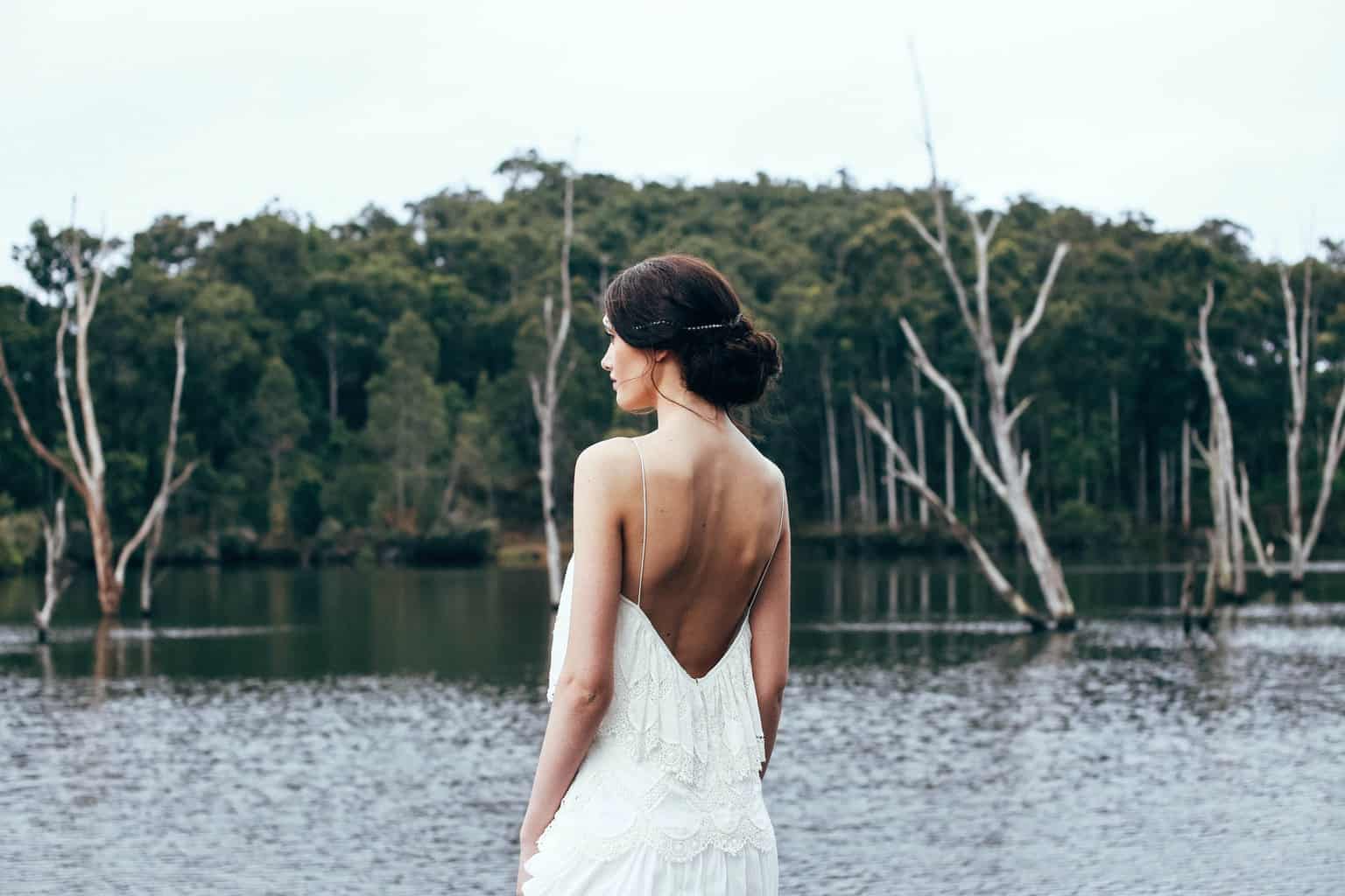 Anonymous elegant bride standing near lake