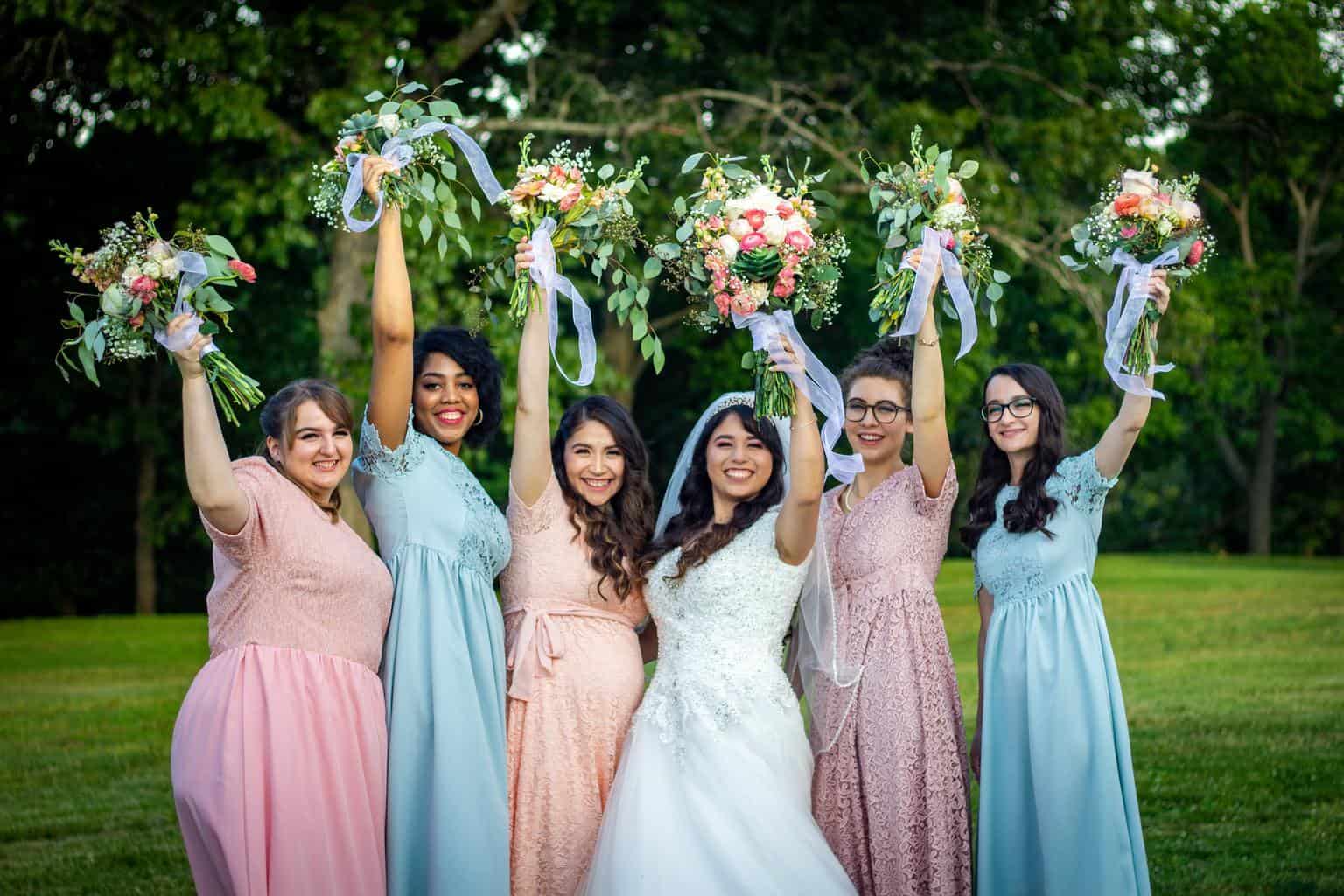 group of women in pink dresses holding bouquet of flowers