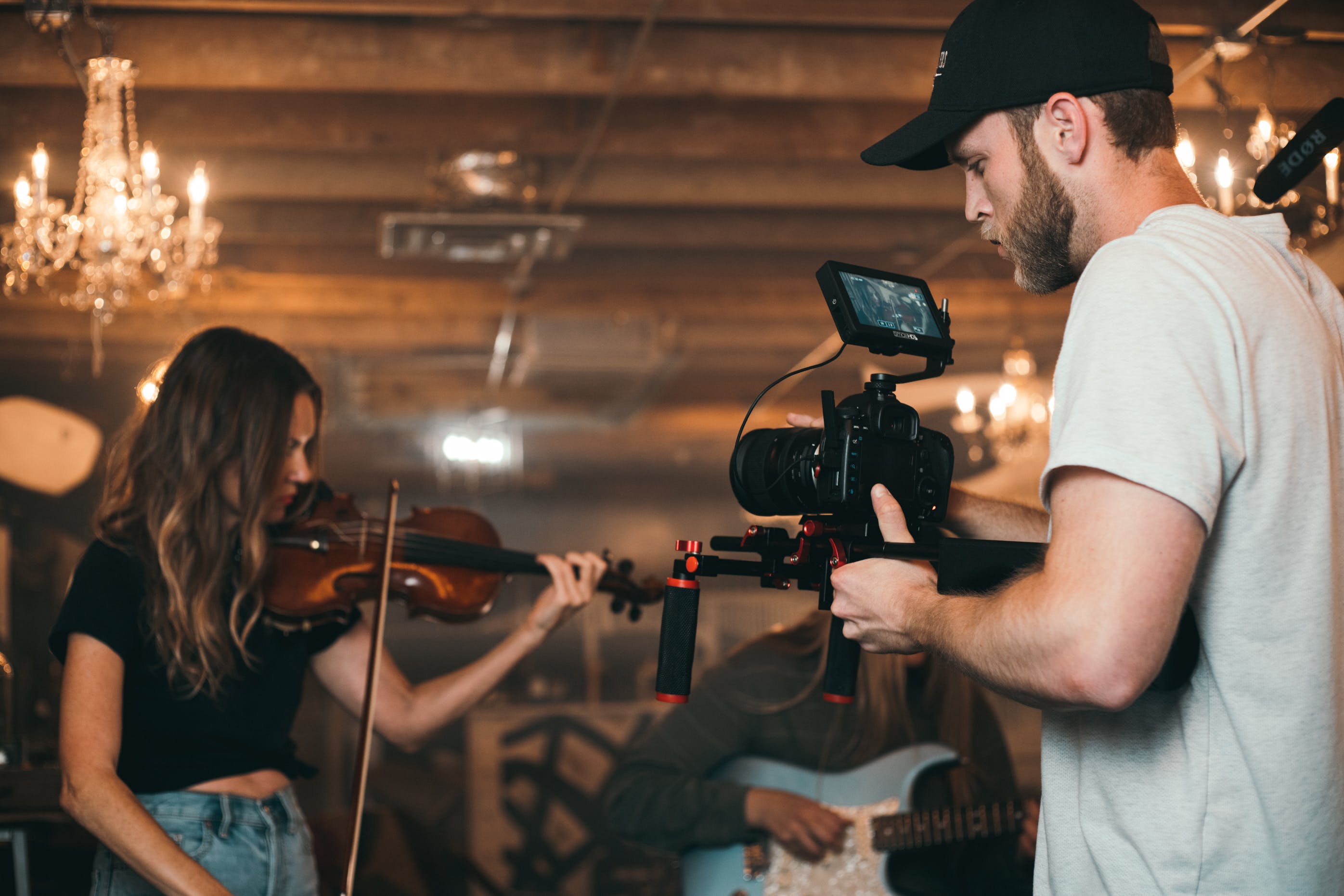 Free Man Holding Camera and Woman Playing Violin Stock Photo