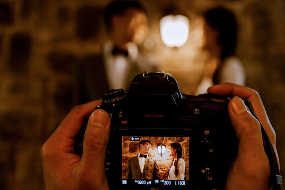 Free A romantic couple captured through a camera screen with warm lighting indoors. Stock Photo